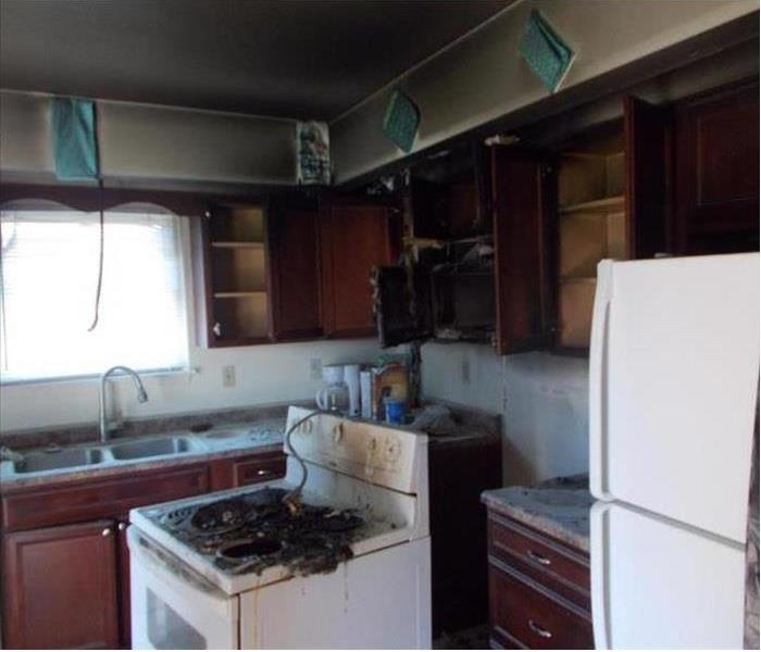 White stovetop and adjacent cabinets are burned